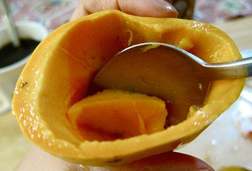 Naudodami šaukštą mango minkštimui išgauti