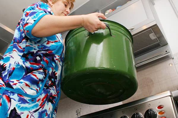 Moteris, laikanti keptuvę skalbiniams virti