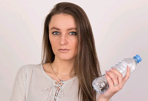 Mergina, laikanti butelį vandens