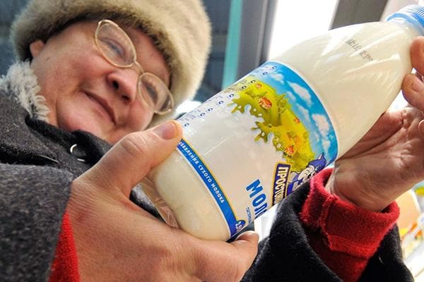 Pensininkas renkasi pieną parduotuvėje