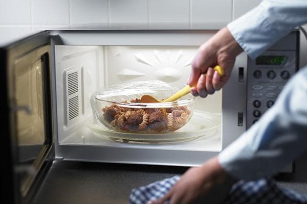 Stiklinis indas su maistu mikrobangų krosnelėje