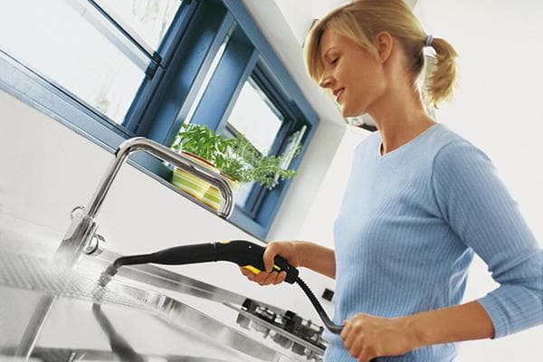 Mujer tratando superficies de cocina con un generador de vapor