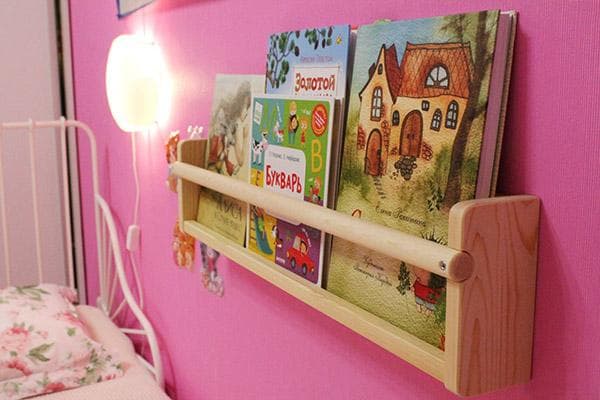 Maža knygų lentyna virš lovos vaikų kambaryje