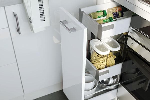 Maisto produktai ir indai apatinėje virtuvės spintelėje