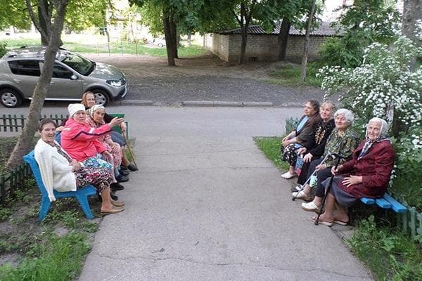 Pensininkai ant suoliukų prie įėjimo
