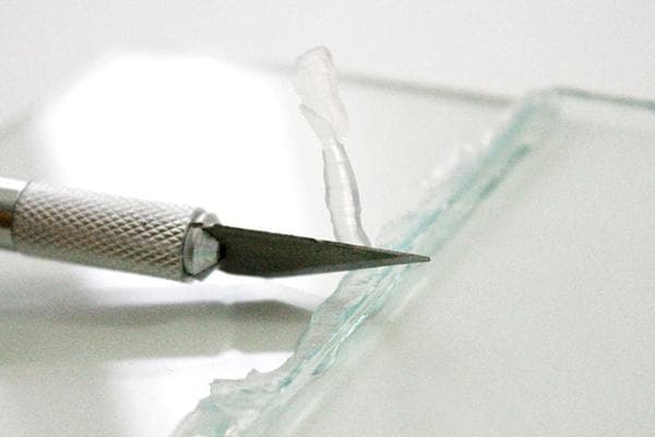Kanceliarinis peilis ir klijų pėdsakai ant stiklo