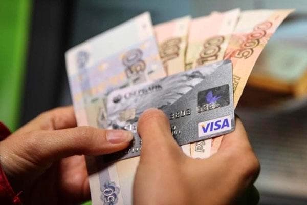 Banknotai ir banko kortelė rankose