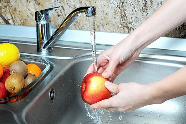 Obuolio plovimas po tekančiu vandeniu